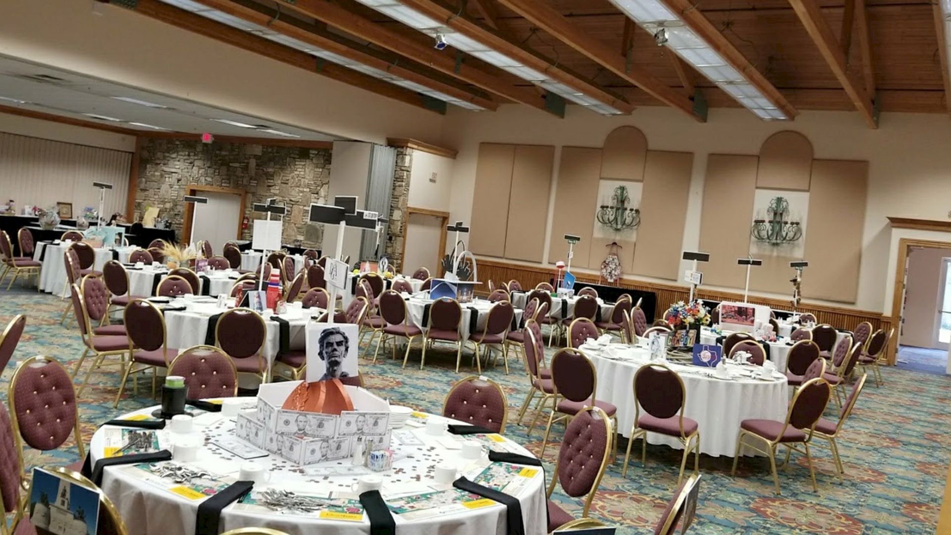 A banquet hall set up with round tables, pink chairs, place settings, and event decor for a large gathering.