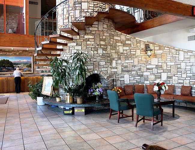 A hotel lobby with a spiral staircase, stone wall, plants, and seating area is visible in the image.