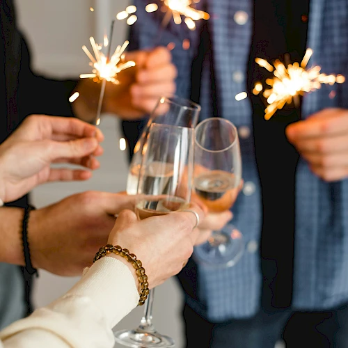A celebration with people toasting sparklers and glasses of champagne. Always ending the sentence.